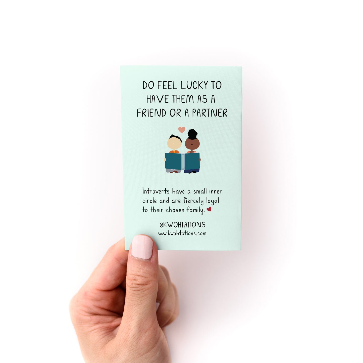 Hand holding "How to Care For Your Introvert Zine" card with friendly introvert quote on light blue background.