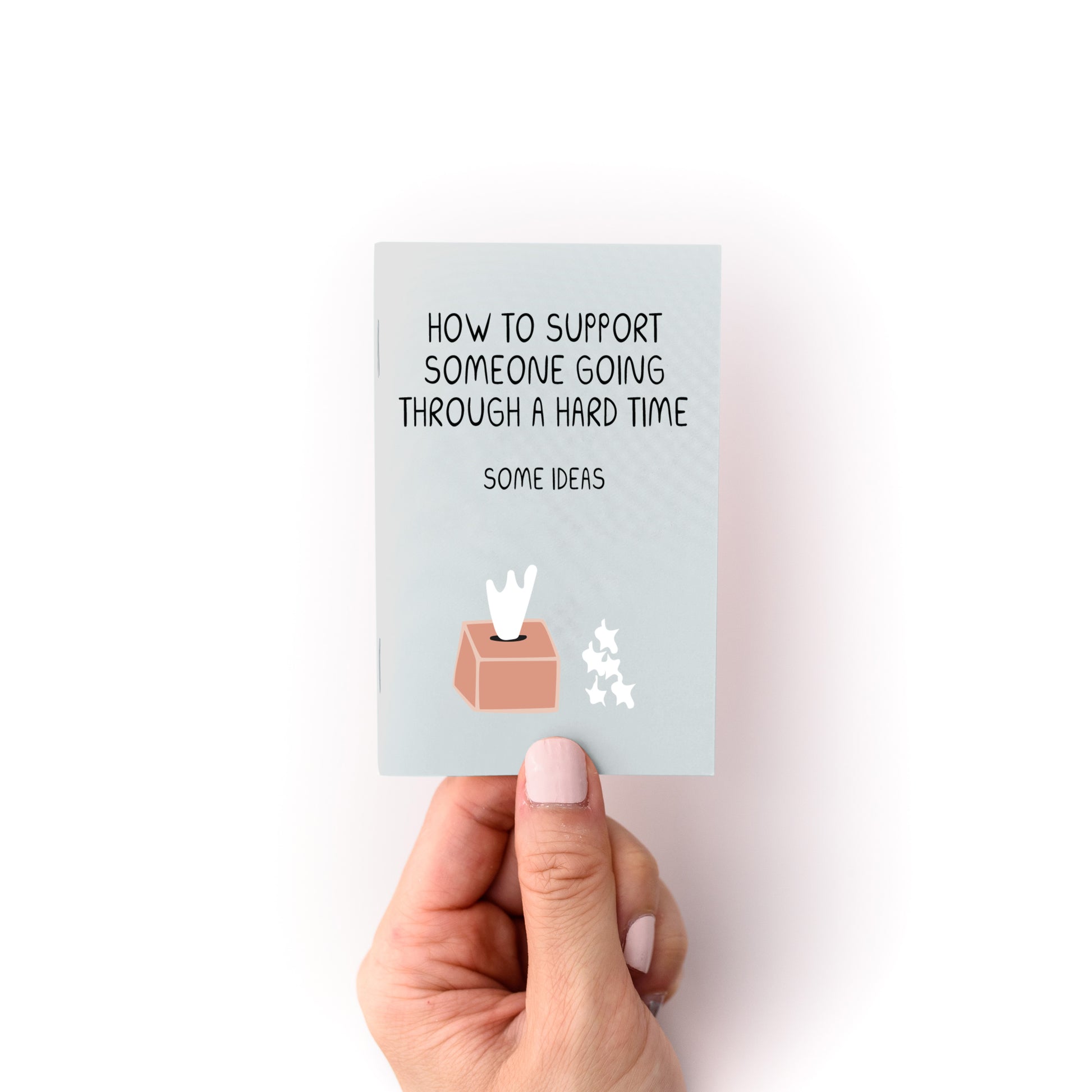Hand holding "How to Support Someone Zine" with tips for supporting someone through a hard time.