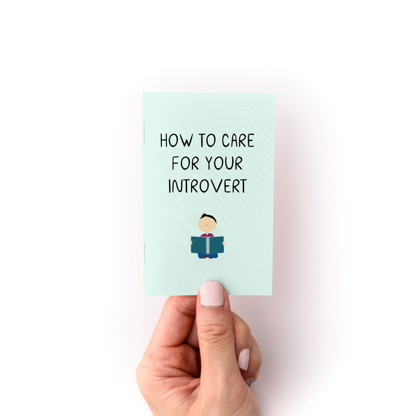 Hand holding the "How to Care For Your Introvert Zine" with a minimalist illustration on cover.