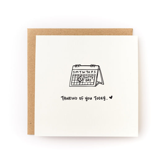 Thoughtful sympathy card for a death anniversary or a hard day. The card has a white background and black illustration of a calendar with a date circled that says, Shitty Day. The card text reads, Thinking of You Today.