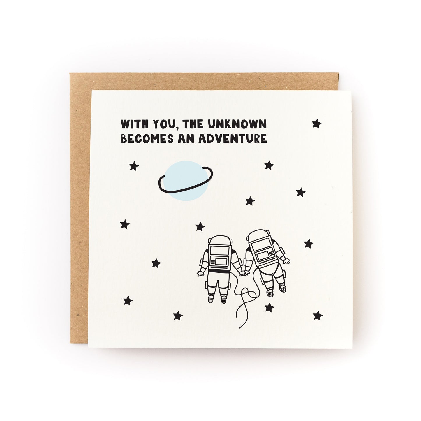 With You the Unknown Becomes an Adventure Letterpress Card with two astronauts holding hands among stars and a planet.