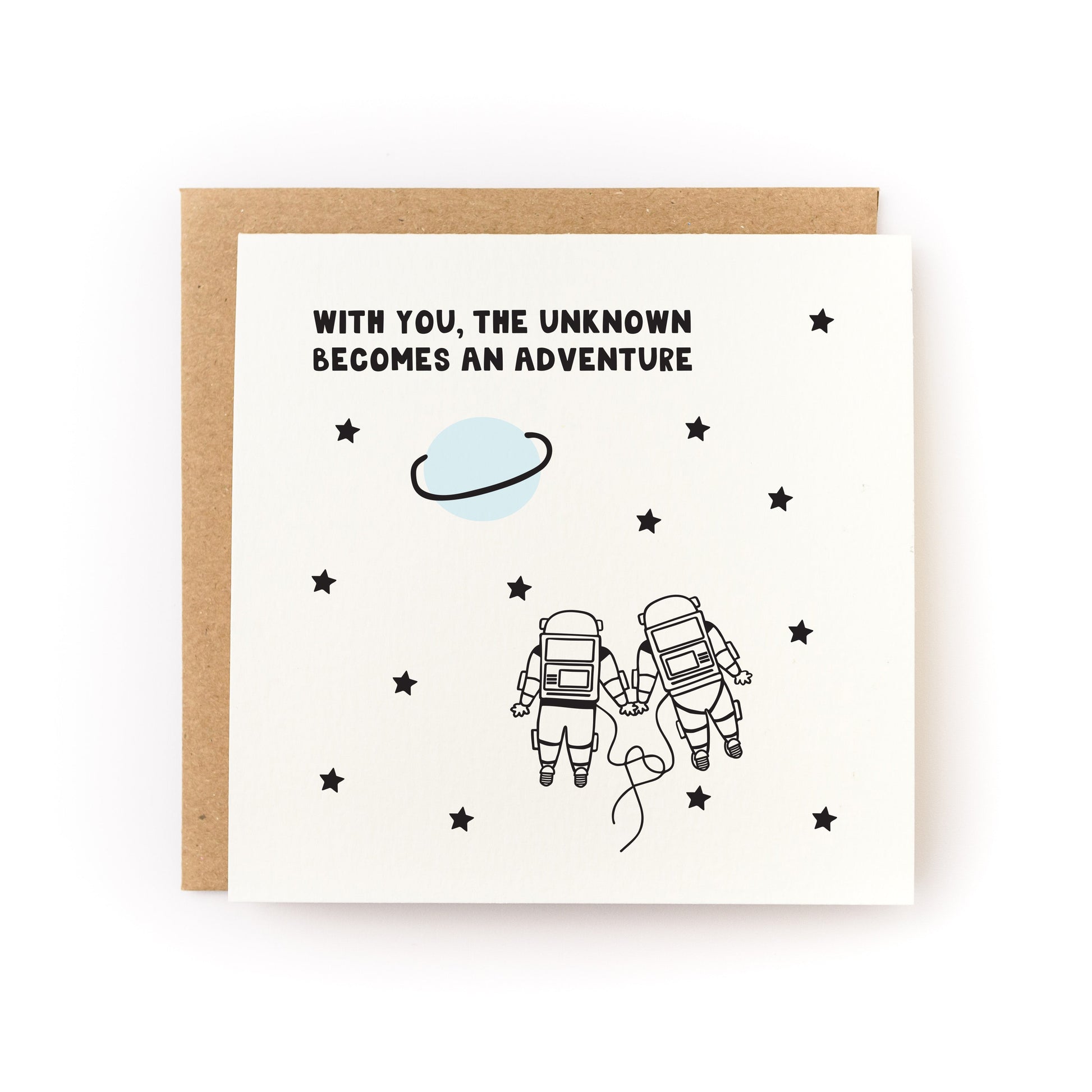 With You the Unknown Becomes an Adventure Letterpress Card with two astronauts holding hands among stars and a planet.
