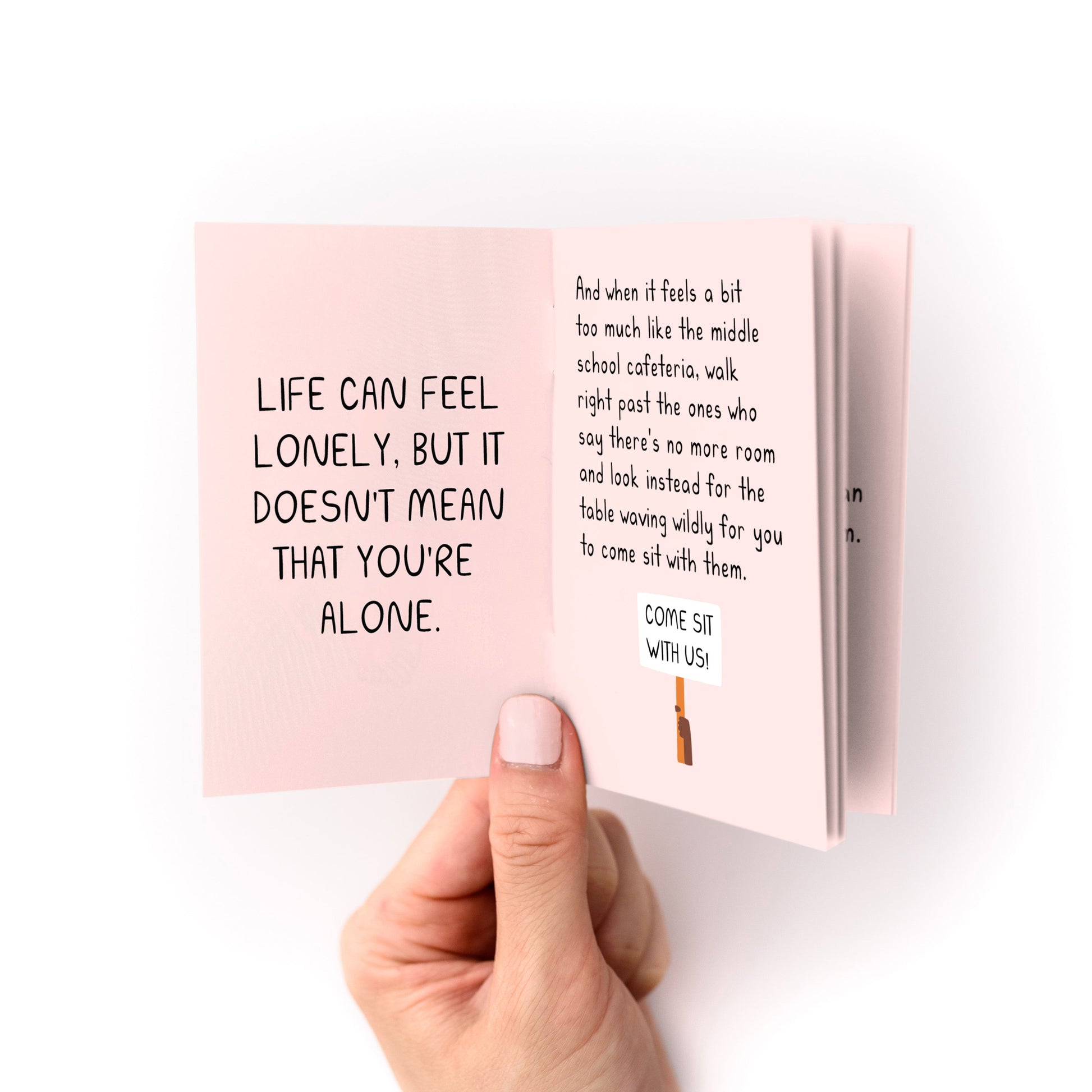 On Belonging (A Tiny Manifesto) Zine held open showing inclusive text on pink heavy cardstock pages.