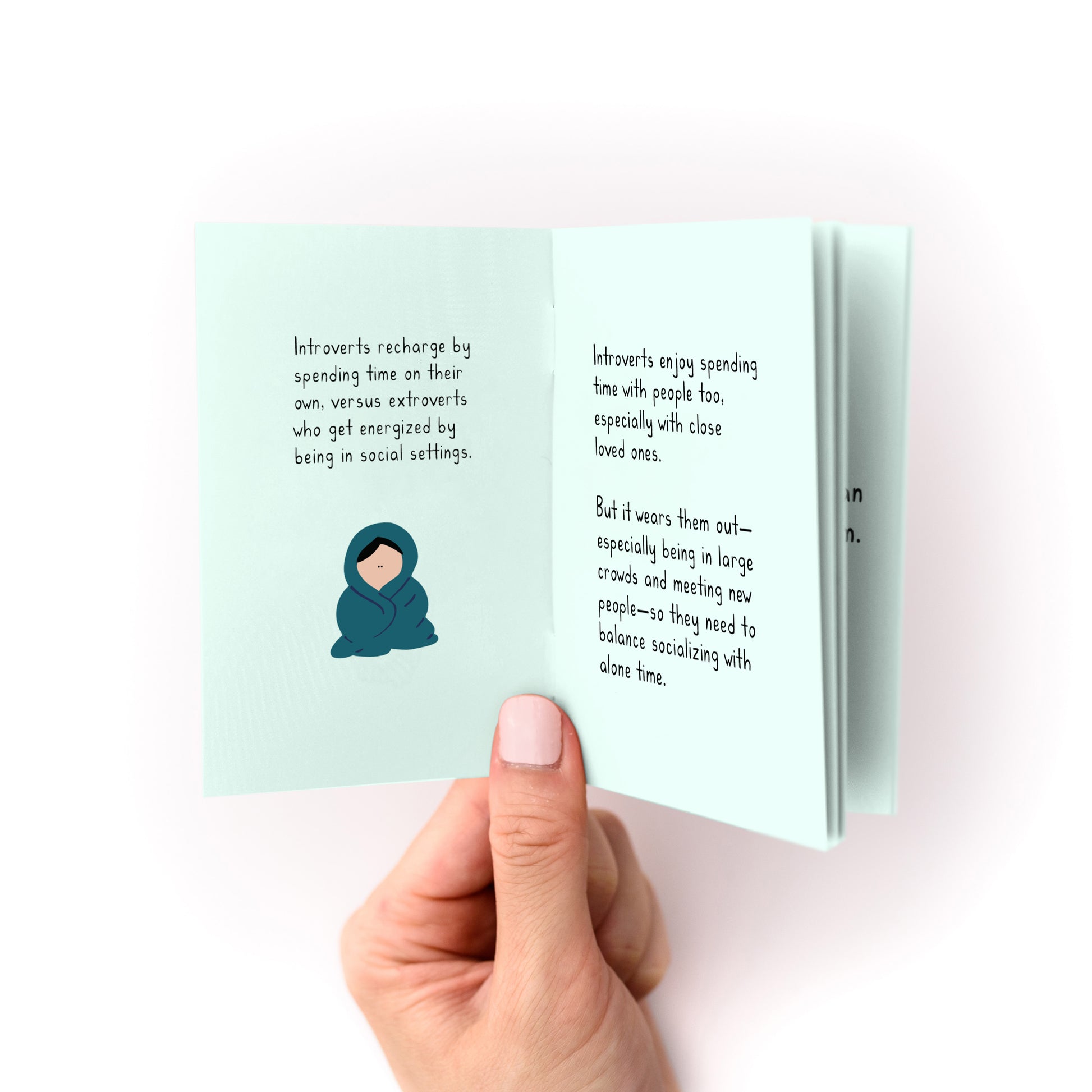 Hand holding open How to Care For Your Introvert Zine showing text and illustration on light blue pages.
