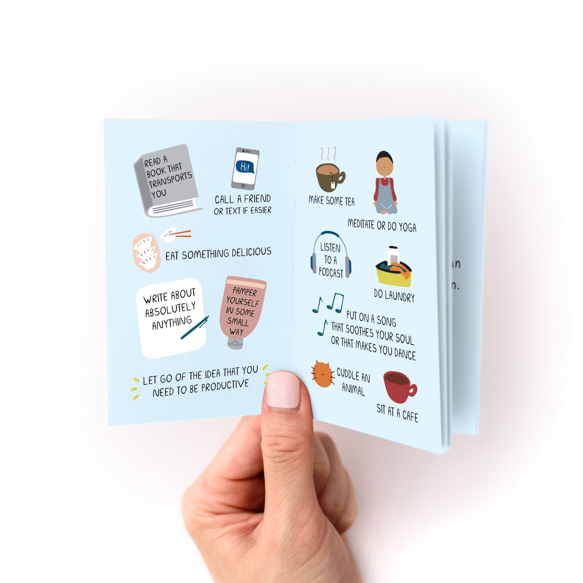 Hand holding "Things to Do When You're in a Depressive Spiral Zine" showing illustrated coping activities and tips.