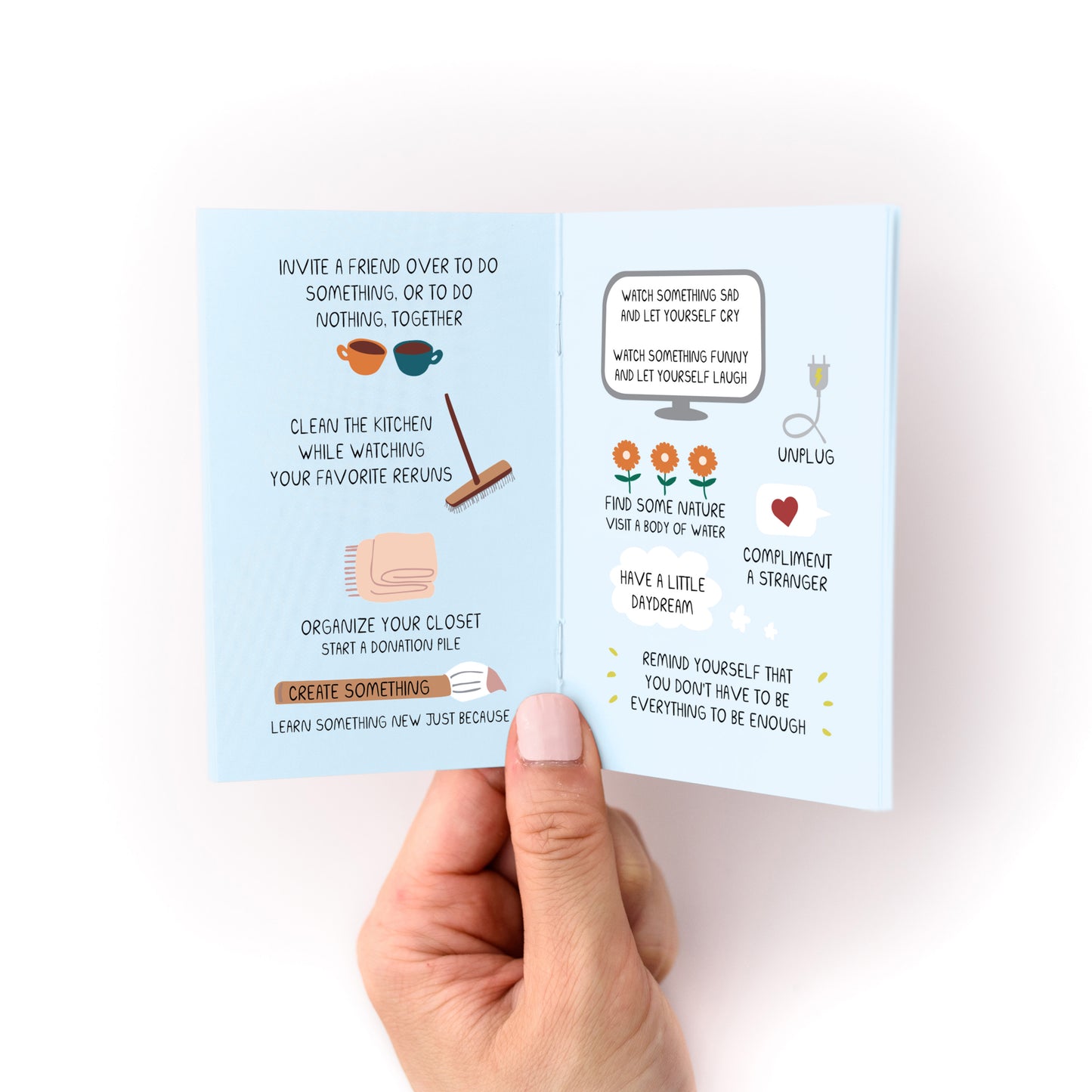 Hand holding open "Things to Do When You're in a Depressive Spiral Zine" showing self-care and activity ideas.