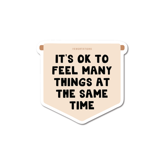 It's OK To Feel Many Things Banner Sticker with bold black text on beige die cut matte vinyl sticker design.