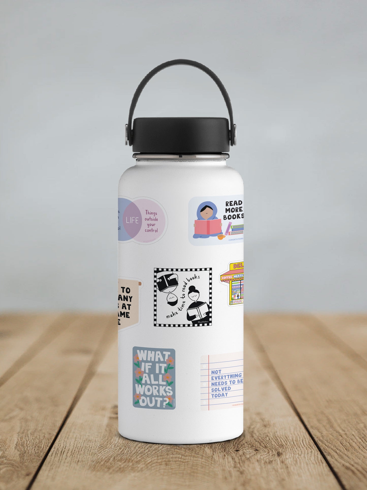 White water bottle with black lid and handle, decorated with various colorful and black-and-white stickers including a person reading a book, a motivational quote about life priorities, and a sticker with hands forming the phrase "make time to read books" inside a checkered border.