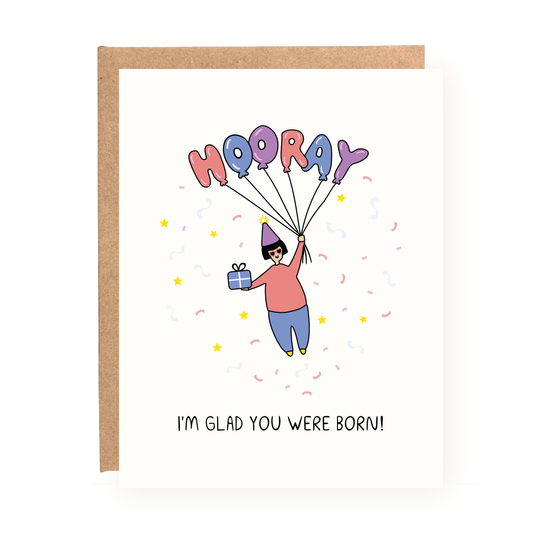 I'm Glad You Were Born Card" birthday card with colorful balloons and person holding a gift on white cardstock with kraft envelope.