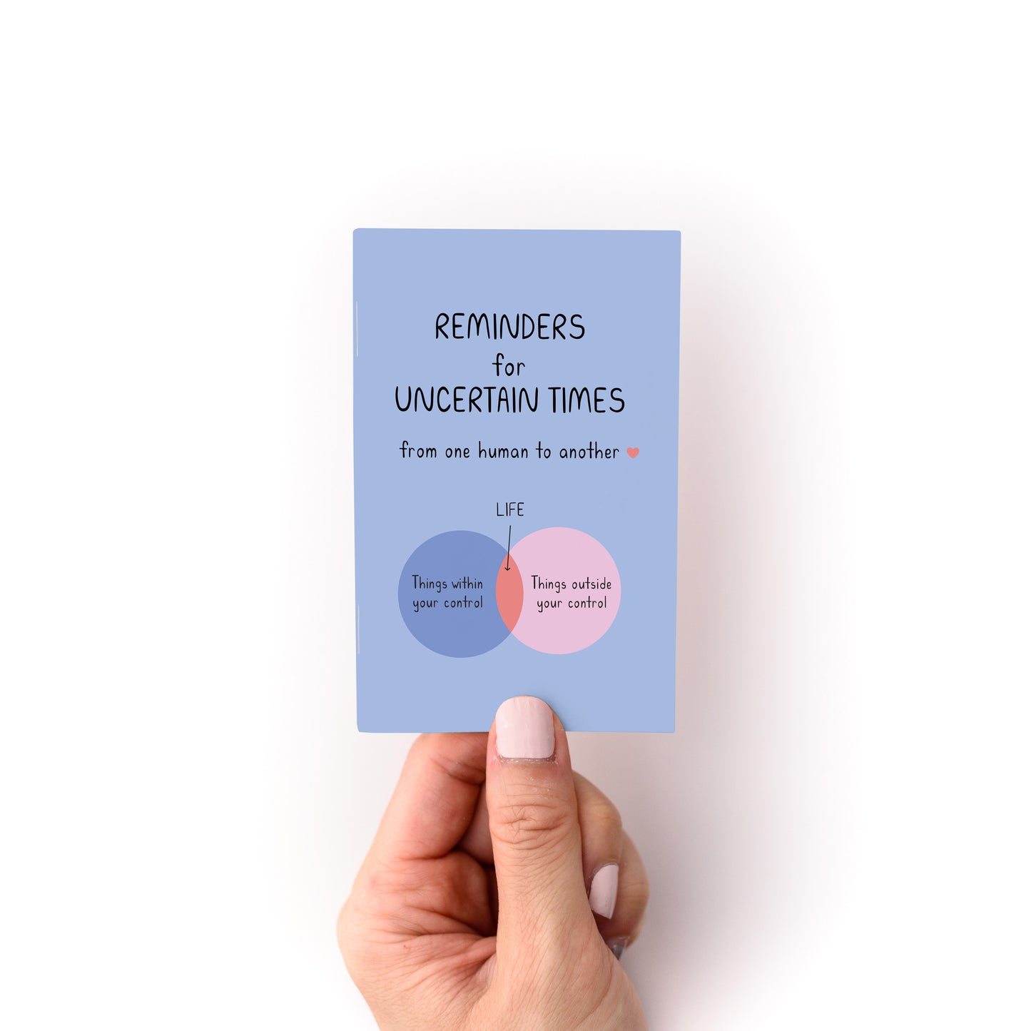 Hand holding the Reminders for Uncertain Times Zine showing a Venn diagram about control and life.