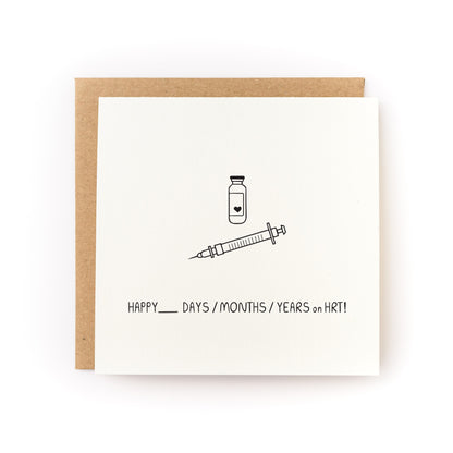 Happy X on HRT! Gender Transition Letterpress Card with syringe and vial illustration on white cardstock.