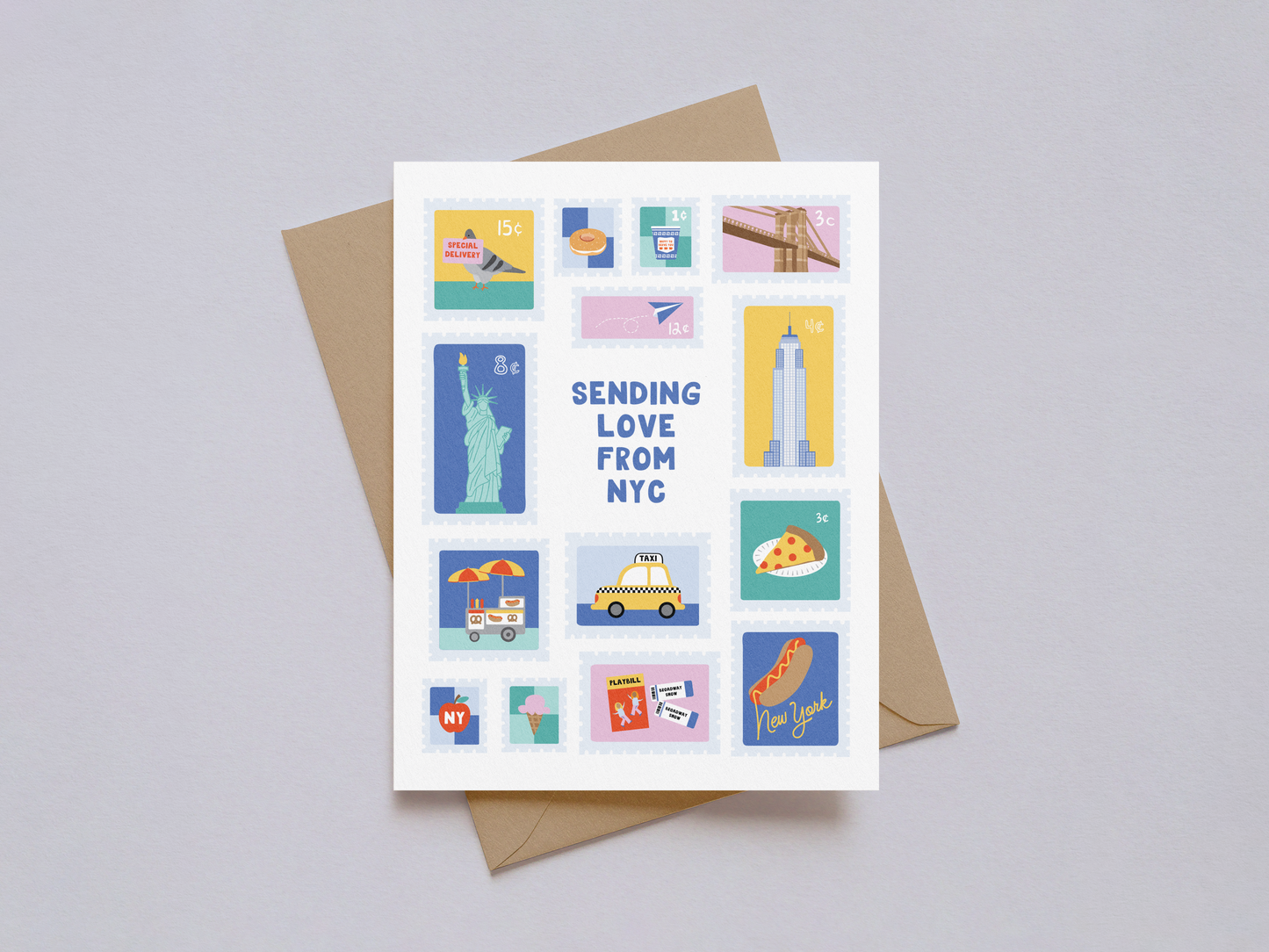 Greeting card designed with colorful illustrated postage stamps featuring New York City landmarks and icons such as the Statue of Liberty, Empire State Building, Brooklyn Bridge, taxi, pizza slice, street food cart, and hot dog, with "Sending Love From NYC" text in the center, set against a white background with a brown kraft envelope underneath.
