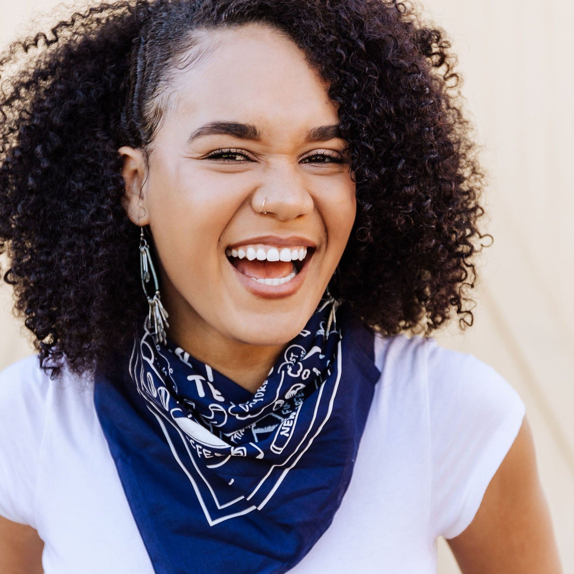 Navy blue cotton bandana with fun screen printed design in white ink. The bandana artwork includes the phrase "Not Everything is Terrible" and hand drawn illustrations of everyday joys, like dumplings, being cozy, shared meals, new socks, getting real mail, and finding the perfect song.