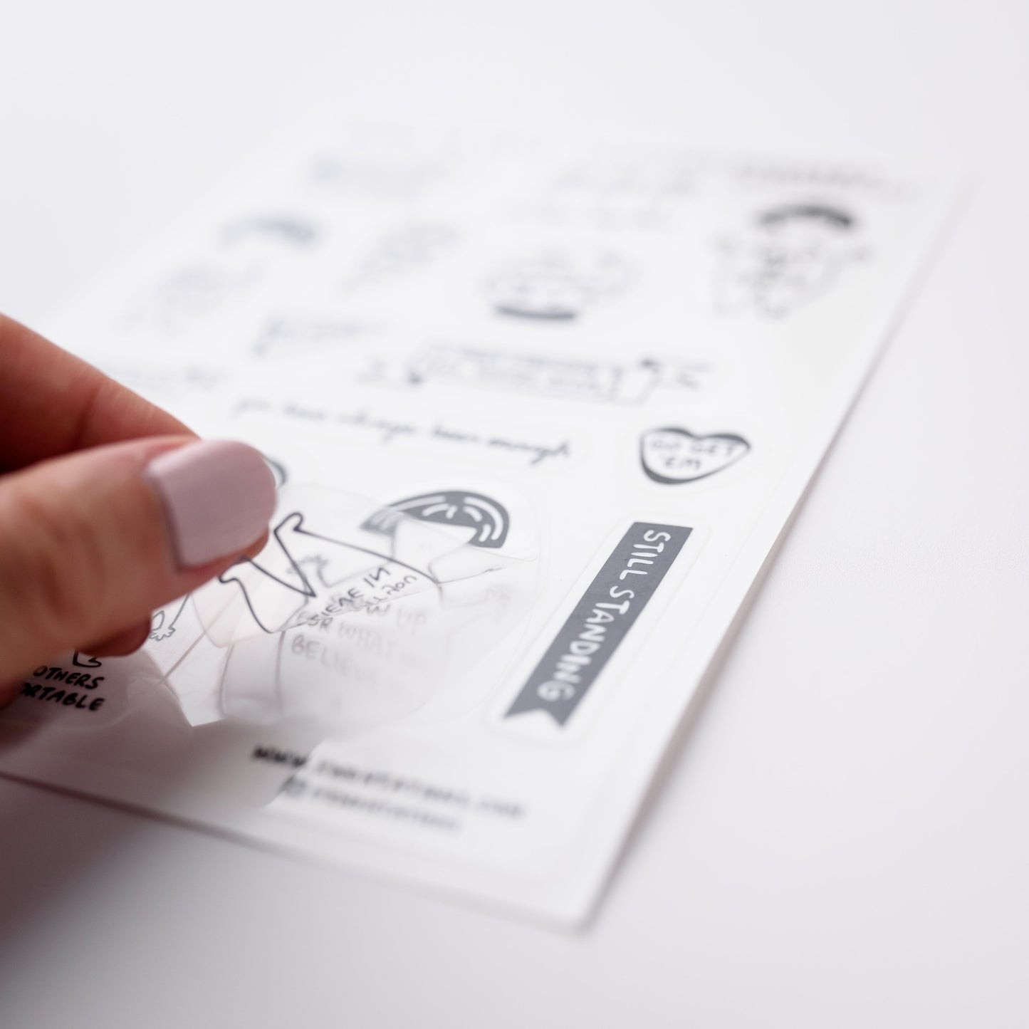 Photo of a hand holding a cute clear sticker.  The sticker has a positive feminist and intersectional message that says, Show Up For What You Believe In.