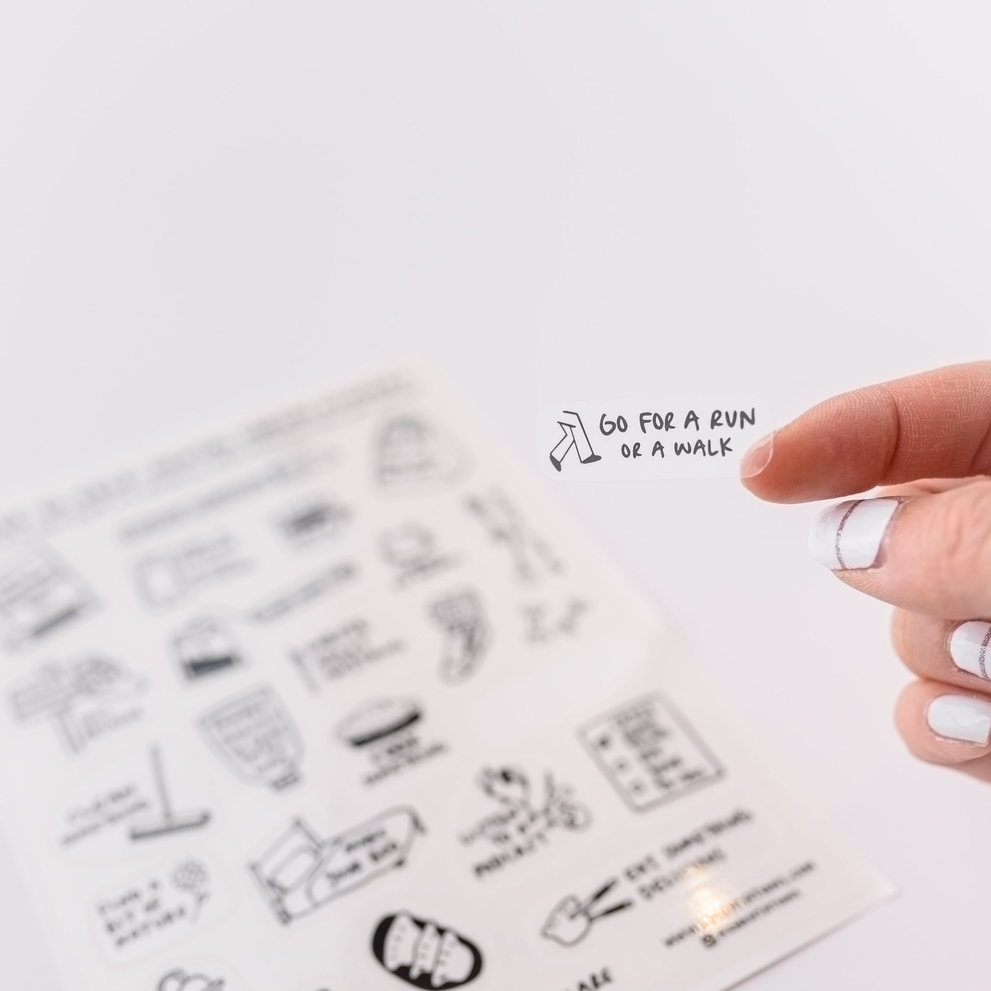 Photo of a hand holding a cute clear sticker.  The sticker has a motivational mental health message that says, Go For A Run Or A Walk.