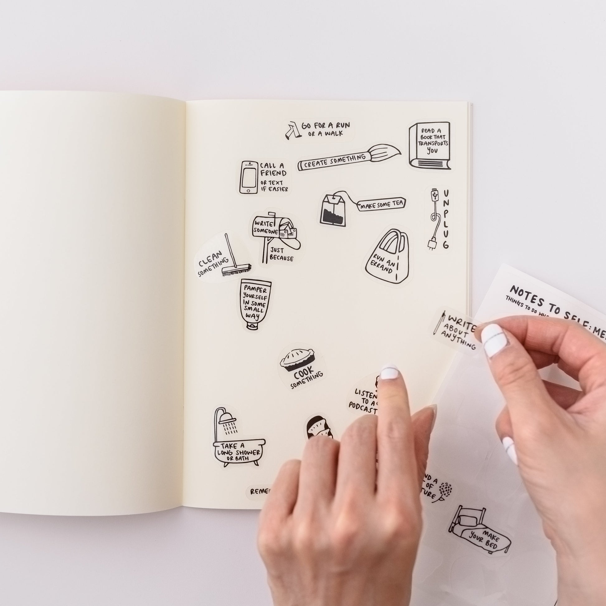 Photo of a hand holding a cute clear sticker.  The sticker has a motivational mental health message that says, Write About Anything