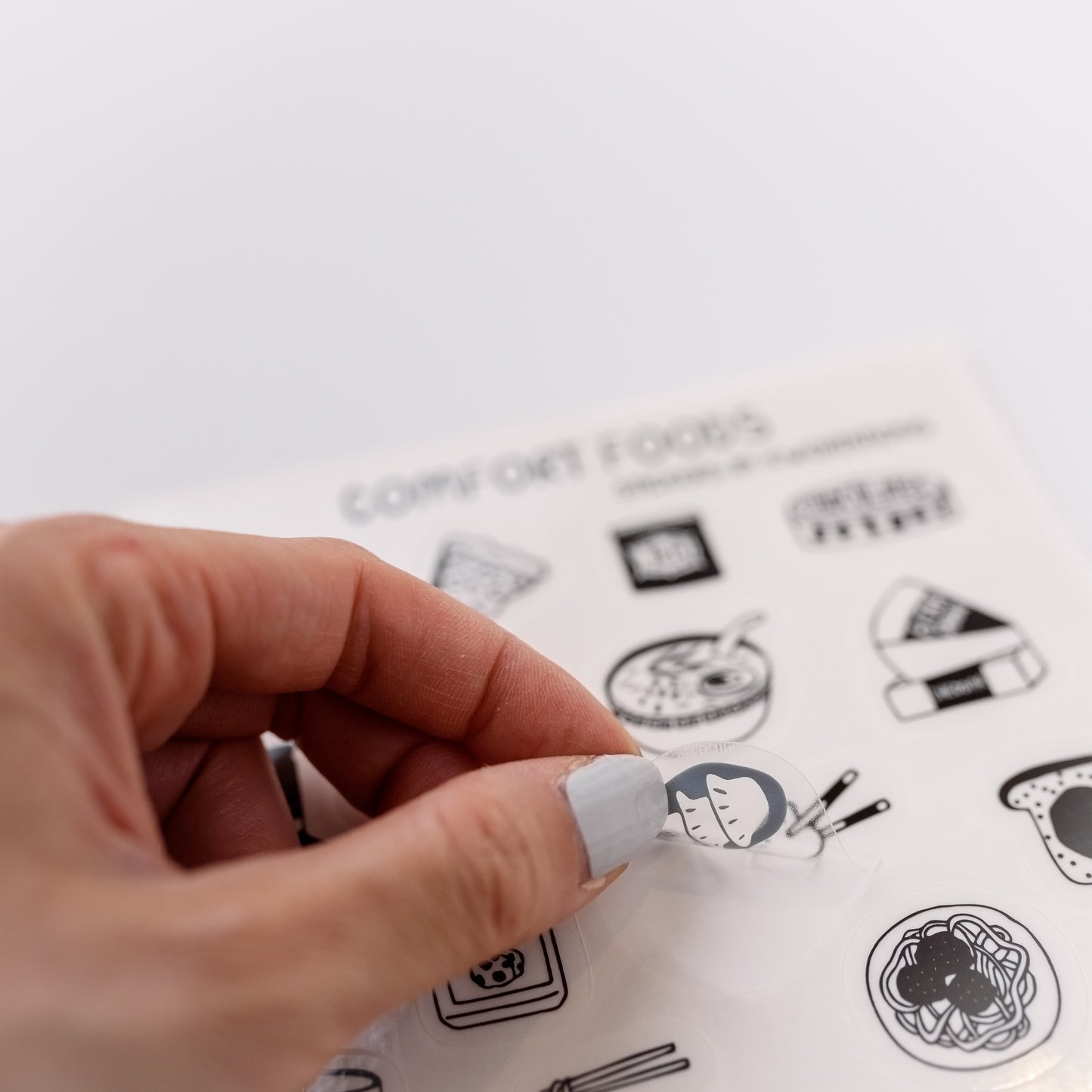 Photo of a hand holding a cute clear sticker.  The sticker has an illustration of  dumplings