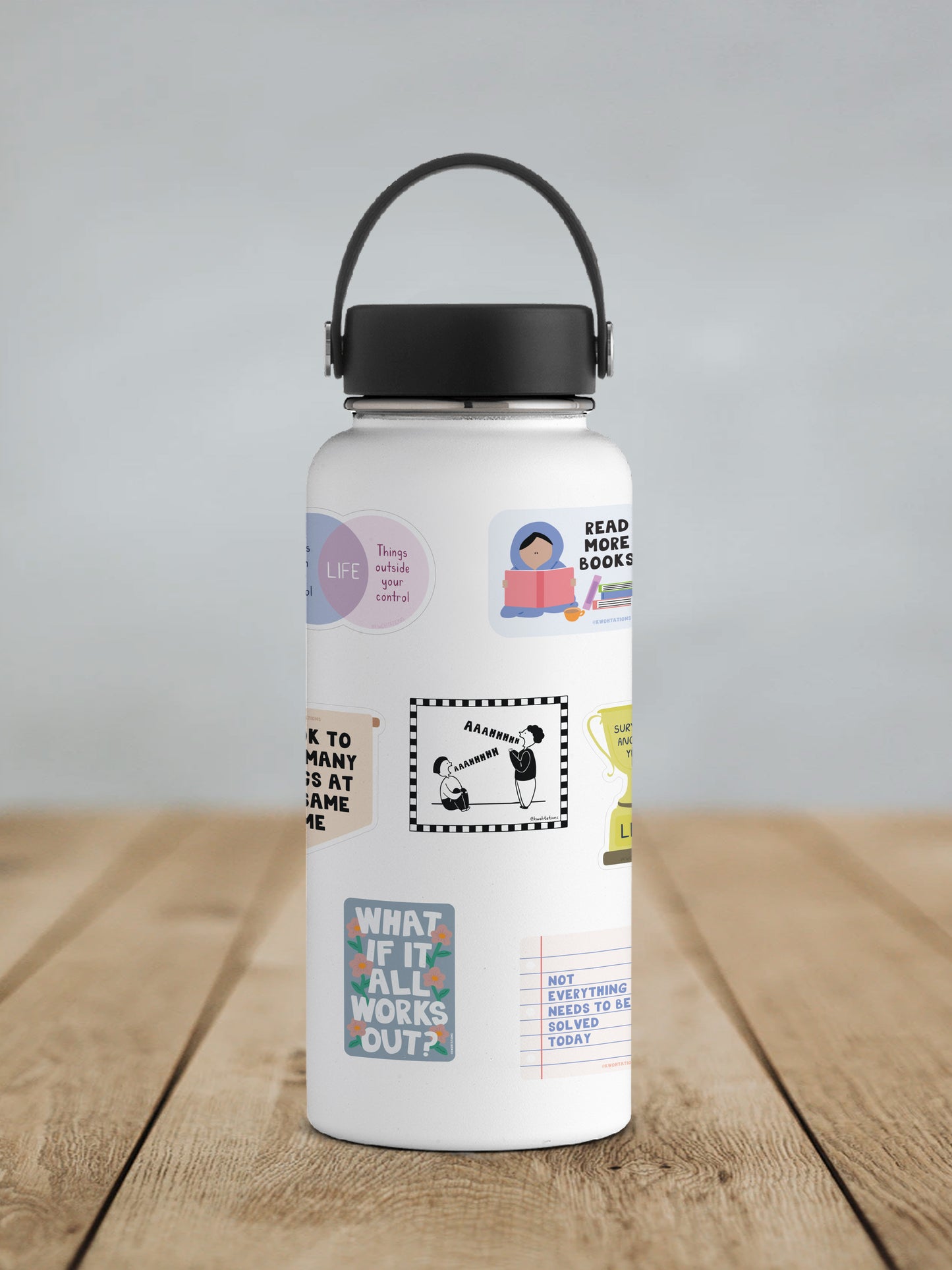 White water bottle with a black lid and handle, decorated with various colorful and black-and-white stickers featuring motivational quotes, illustrations of people, and playful designs.