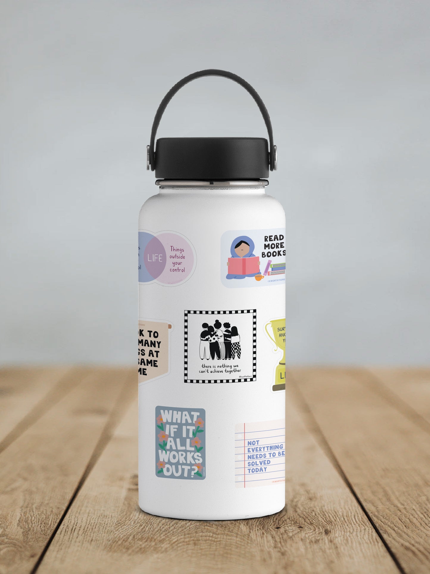 White water bottle with black lid and handle, decorated with various colorful and black-and-white motivational stickers featuring people, inspirational quotes, and playful designs.