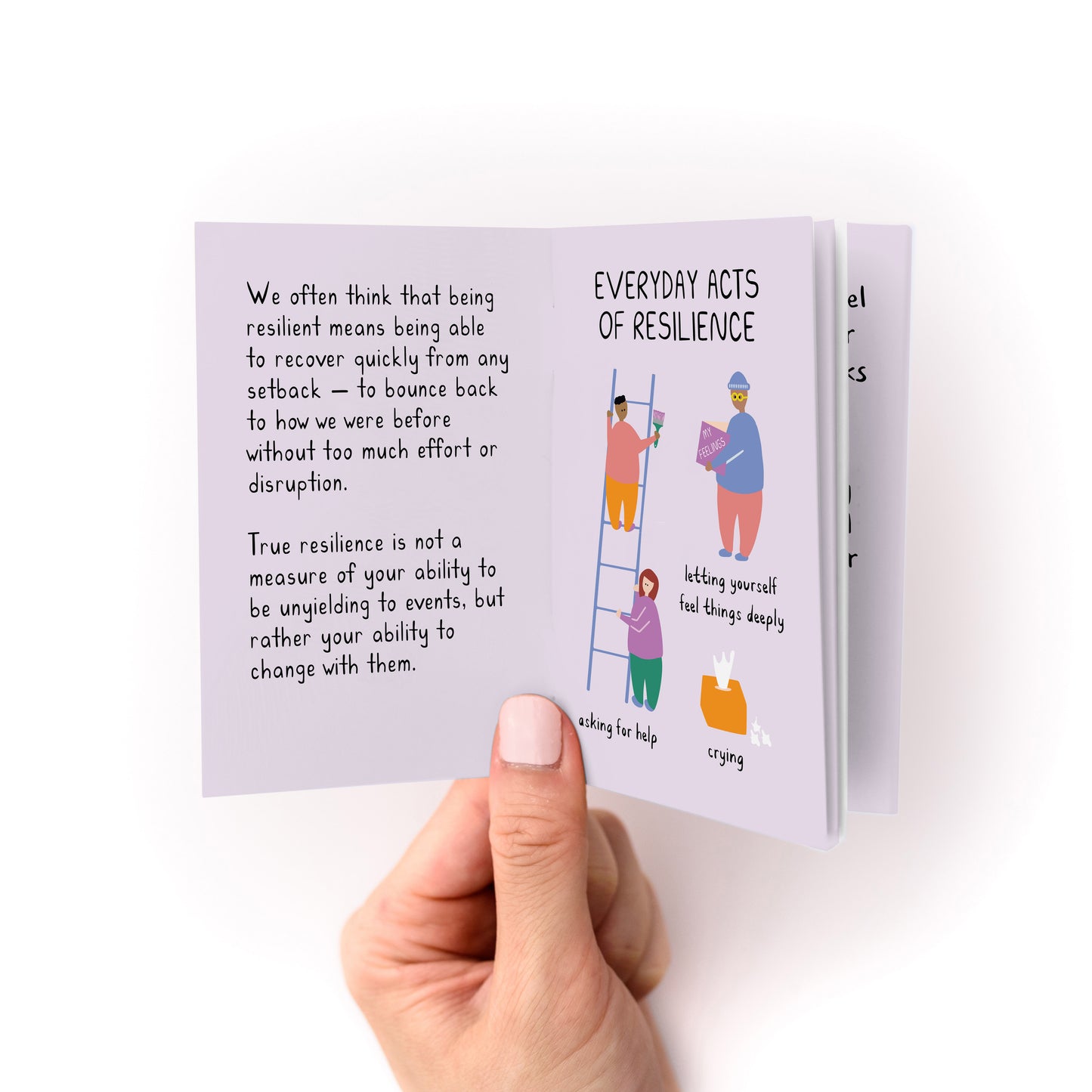 Hand holding open a small booklet showing illustrated text and drawings about everyday acts of resilience on a lavender background