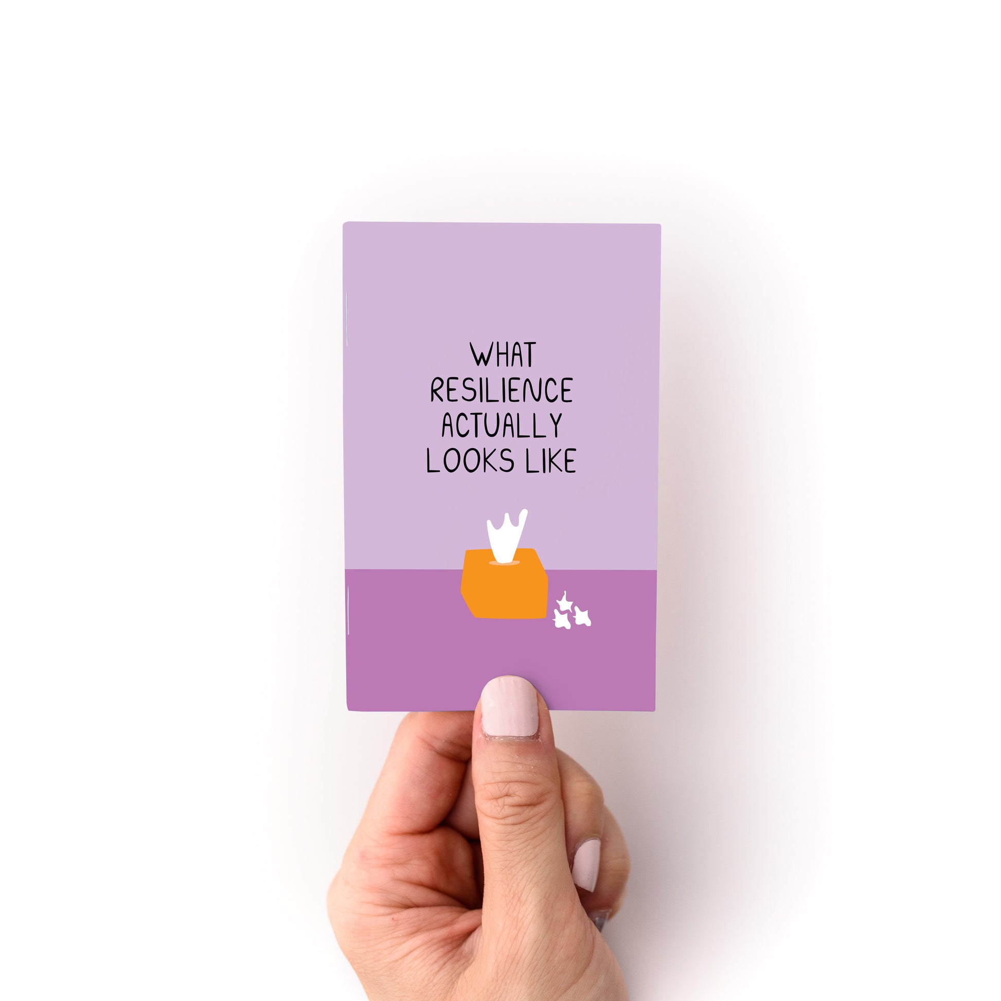 Hand holding a small purple booklet titled What Resilience Actually Looks Like with a tissue box illustration below text